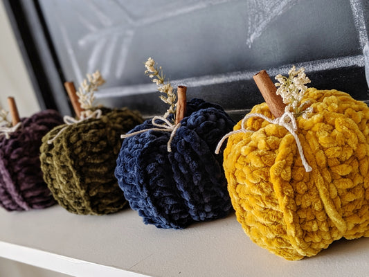 velvet crochet pumpkins in a row on a shelf